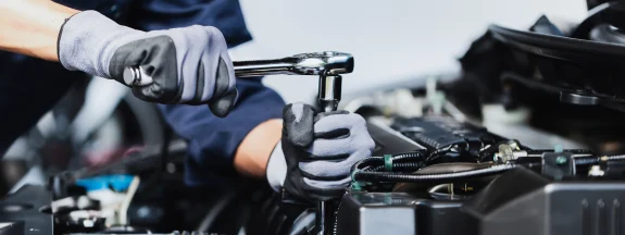 Mekaniker drar åt en skruv i motorrummet med nyckel